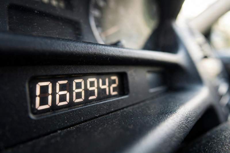 Close-up photograph of a car dashboard odometer showing mileage numbers with shallow depth of field in daylight