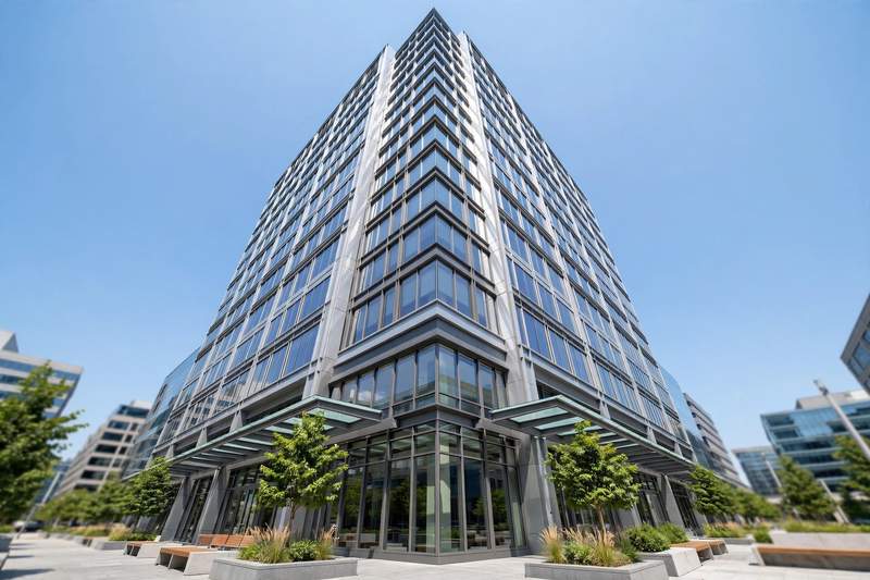 Modern glass office building exterior viewed from a low angle under a clear blue sky